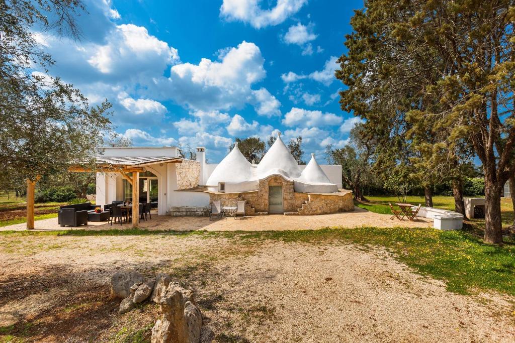 une maison avec un toit blanc sur un champ dans l'établissement Trullo Melograno by Perle di Puglia, à San Michele Salentino