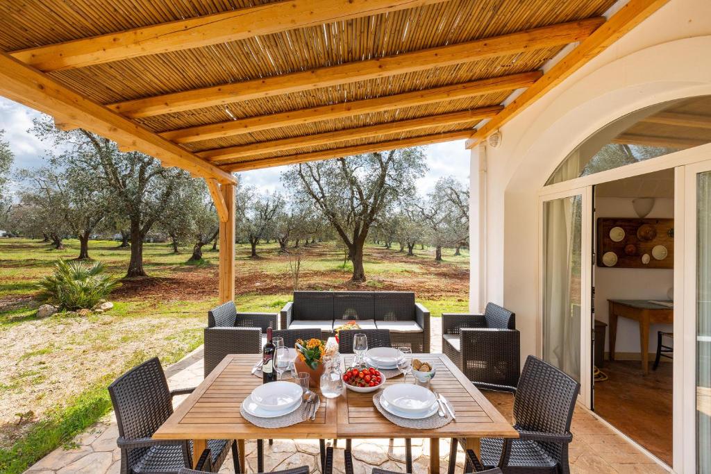 une table et des chaises en bois sous une pergola en bois dans l'établissement Trullo Melograno by Perle di Puglia, à San Michele Salentino