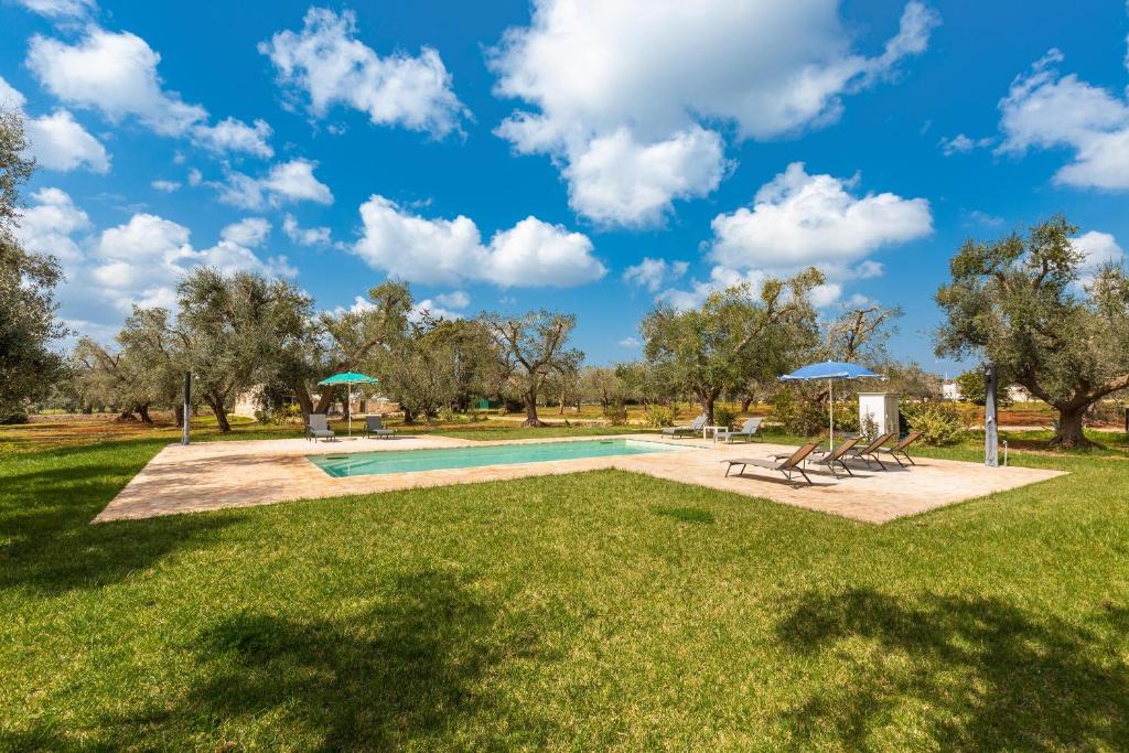 une piscine avec des chaises et des parasols dans un parc dans l'établissement Trullo Melograno by Perle di Puglia, à San Michele Salentino
