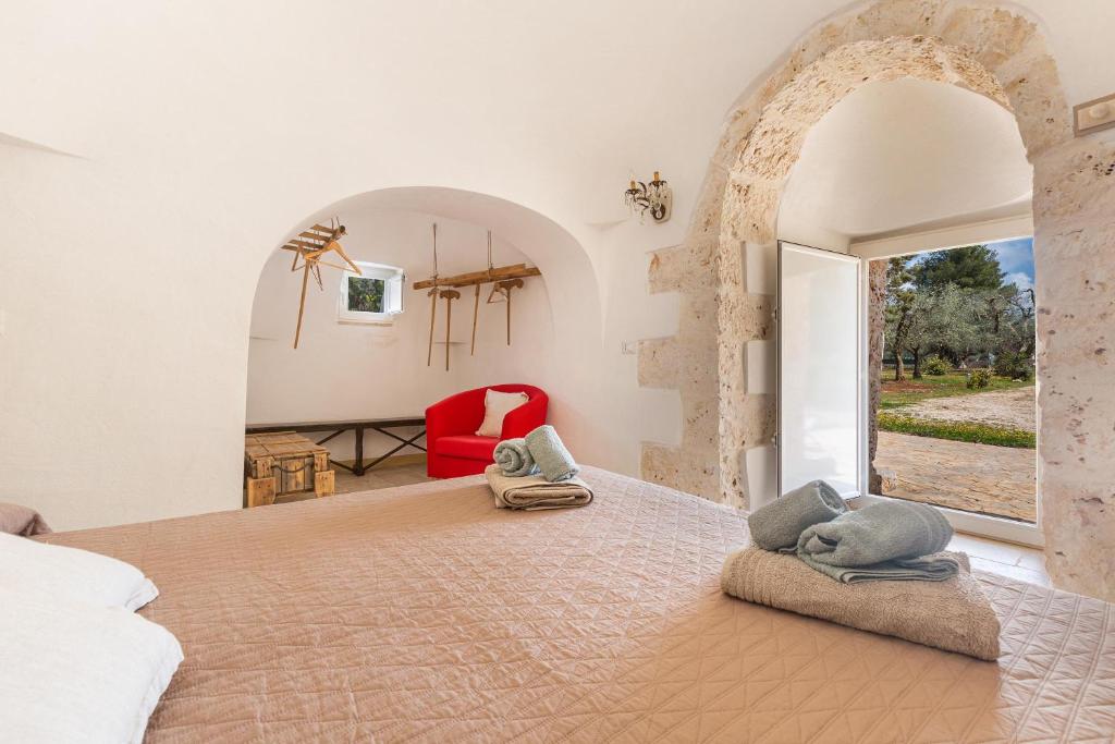 une chambre avec un grand lit et une chaise rouge dans l'établissement Trullo Melograno by Perle di Puglia, à San Michele Salentino