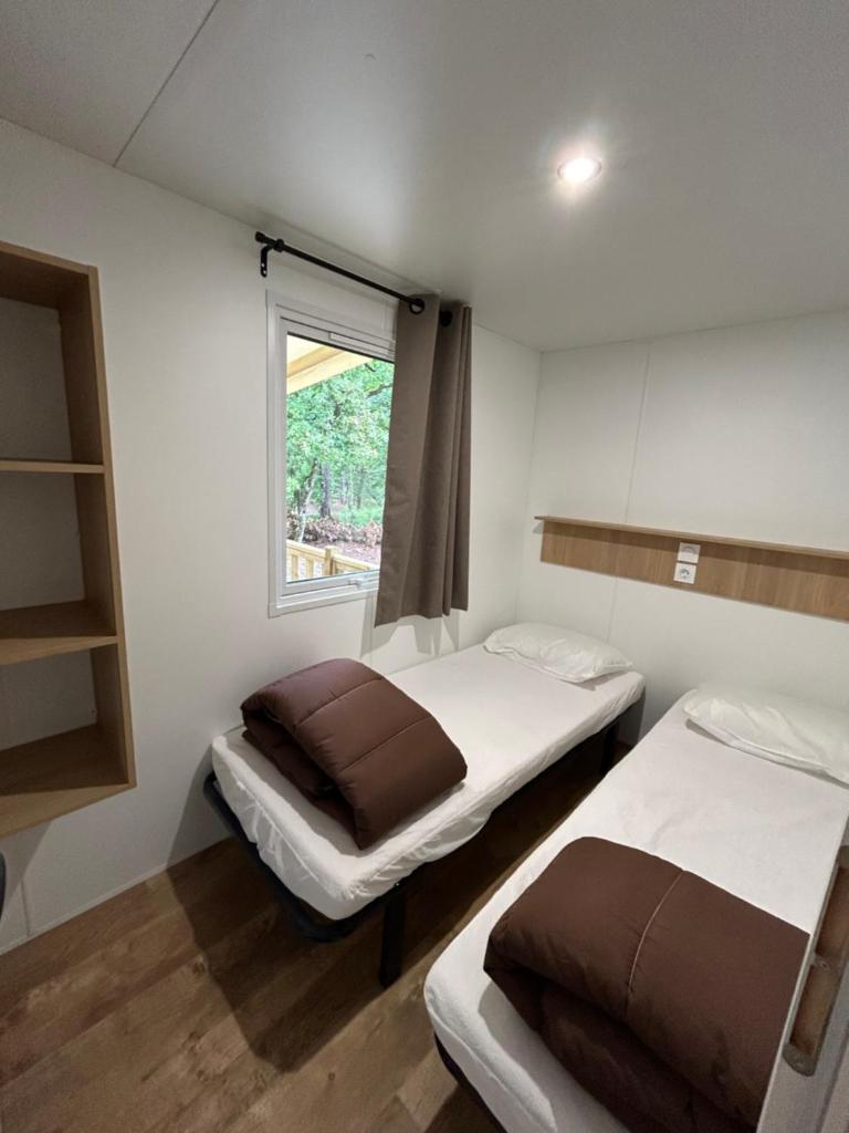 deux lits dans une petite pièce avec une fenêtre dans l'établissement Mobil home ile de loisirs de buthiers, à Buthiers 14 autres photos