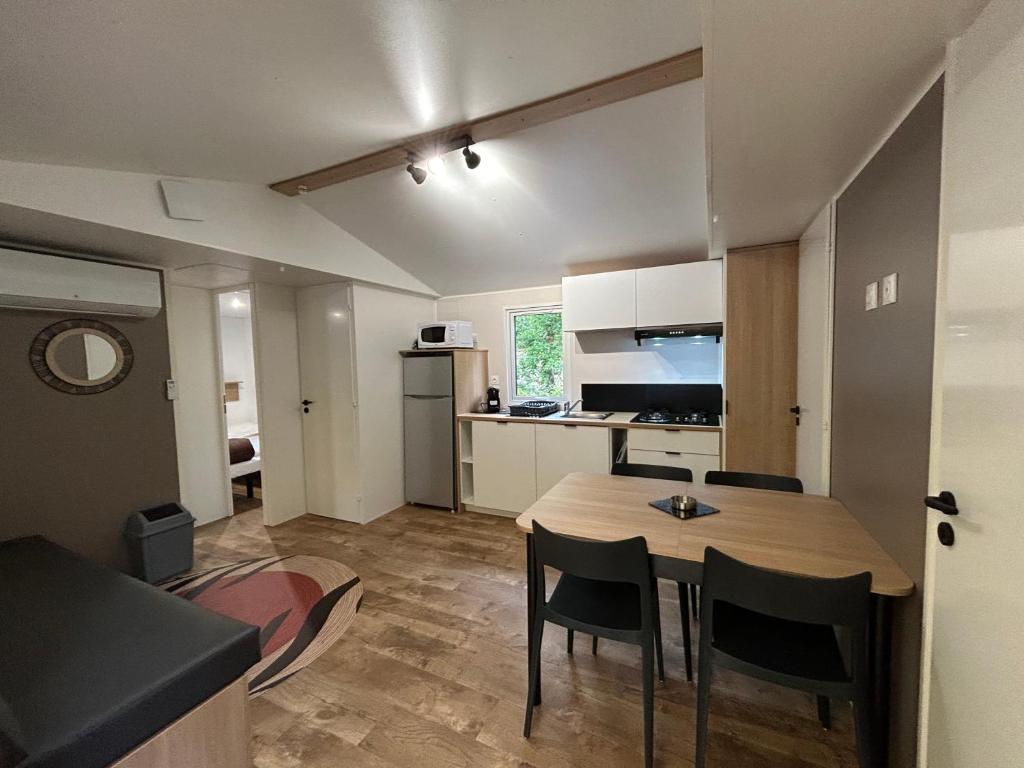 une cuisine et une salle à manger avec une table et des chaises dans l'établissement Mobil home ile de loisirs de buthiers, à Buthiers