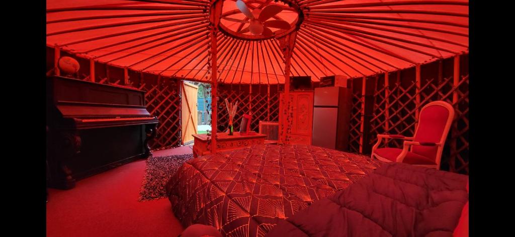 une chambre rouge avec un lit et un piano dans l'établissement La Yourte, à Vinassan