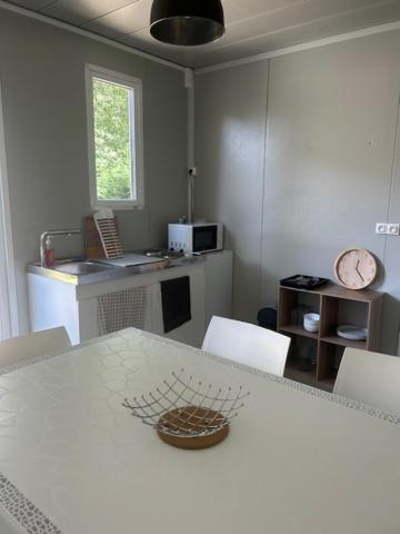 une cuisine avec une table blanche, des chaises et un comptoir dans l'établissement Camping de Bernadou - Le Lodge, à Villemur-sur-Tarn