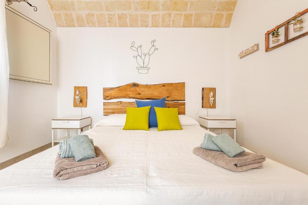 - une chambre dotée d'un grand lit blanc avec des oreillers jaunes et bleus dans l'établissement Trullo Fico by Perle di Puglia, à San Michele Salentino 26 autres photos