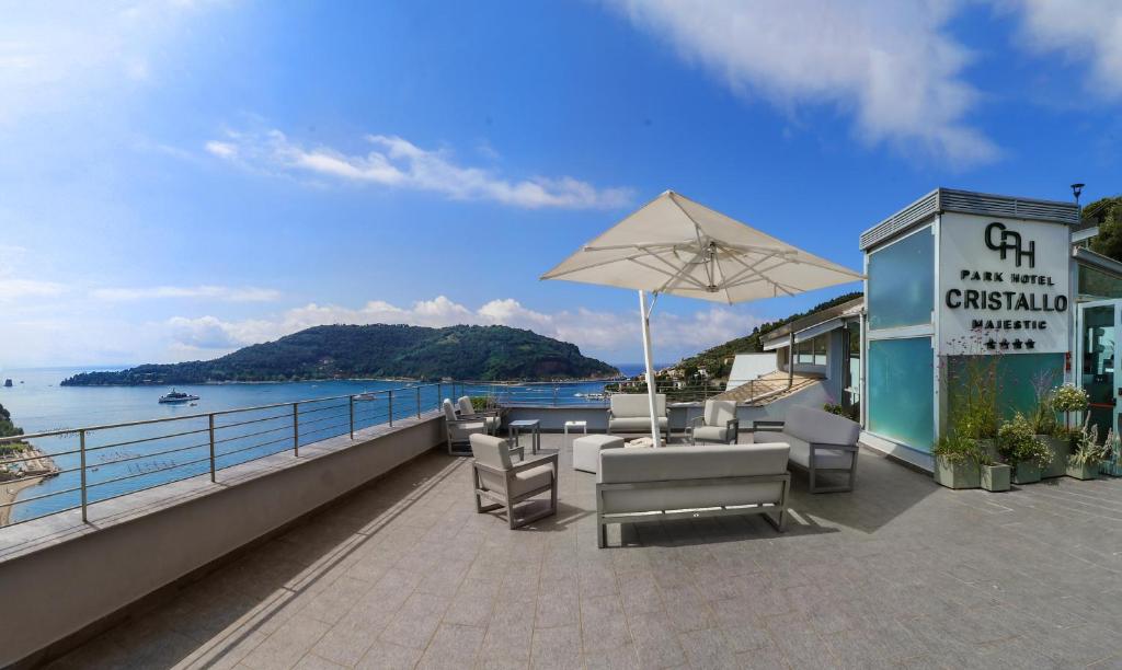 - une terrasse avec des chaises et un parasol à côté de l'eau dans l'établissement Cristallo Park Hotel, à Portovenere