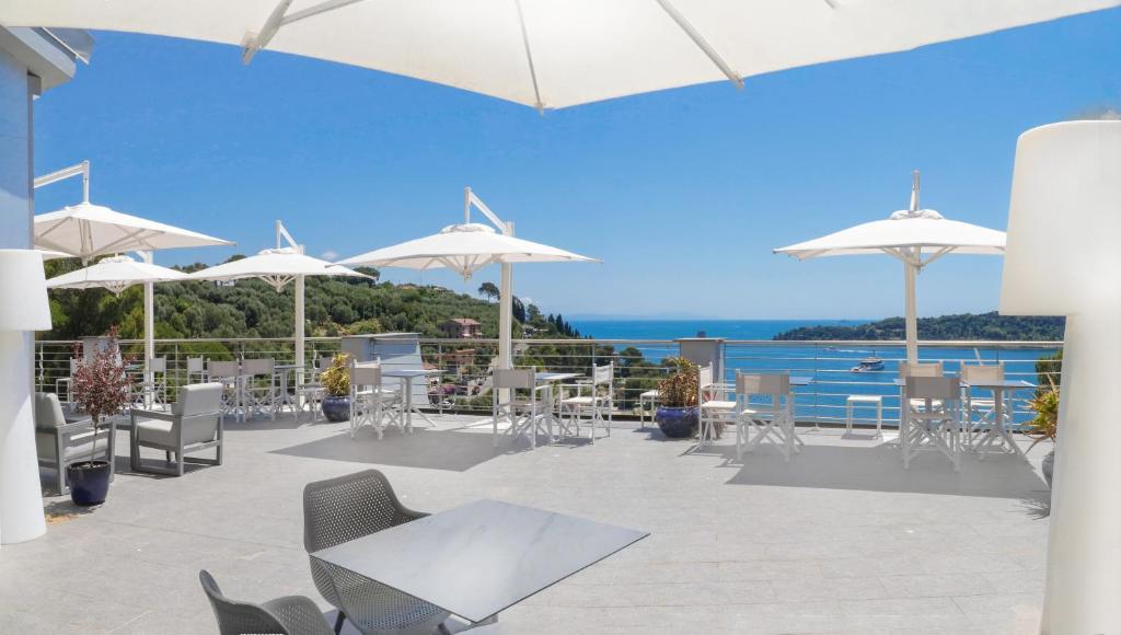 un patio avec tables, chaises et parasols dans l'établissement Cristallo Park Hotel, à Portovenere