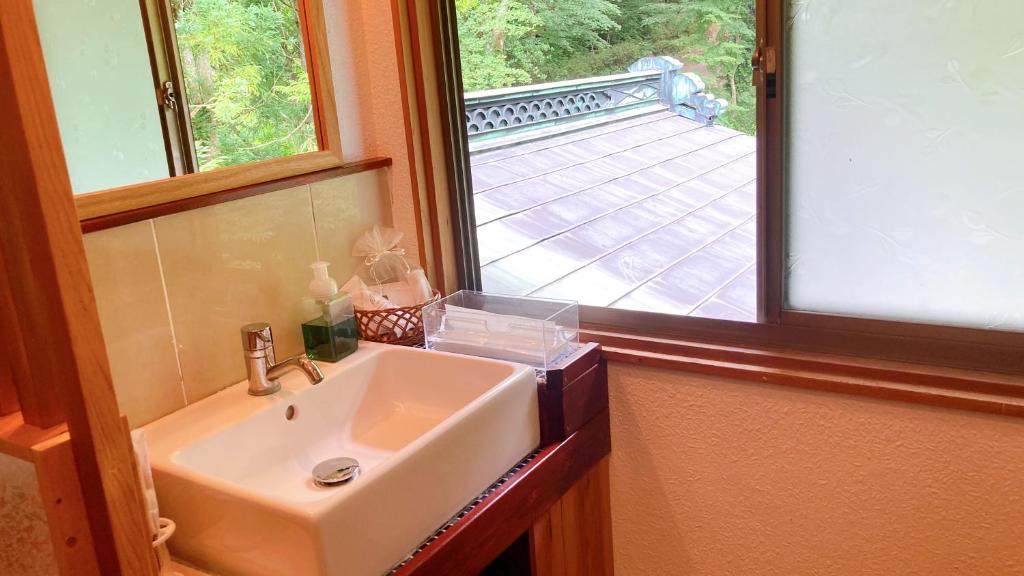La salle de bains est pourvue d'un lavabo blanc et d'une fenêtre. dans l'établissement YUPOPPO Hakone, à Hakone