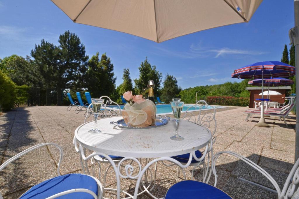 une table blanche avec des verres à vin dessus à côté d'une piscine dans l'établissement Casale Tigli - Happy Rentals, à Capolona