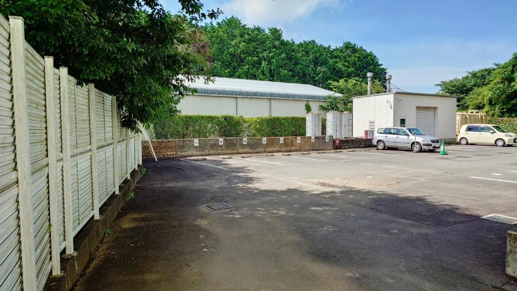 un parking avec clôture et voitures garées dans l'établissement ホテルシエル沼津店 沼津インター -大人専用-, à Numazu