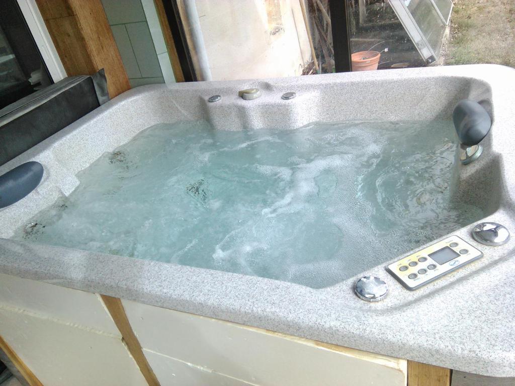 une baignoire remplie d'eau dans un lavabo dans l'établissement Chalet en bois, à Druyes-les-Belles-Fontaines
