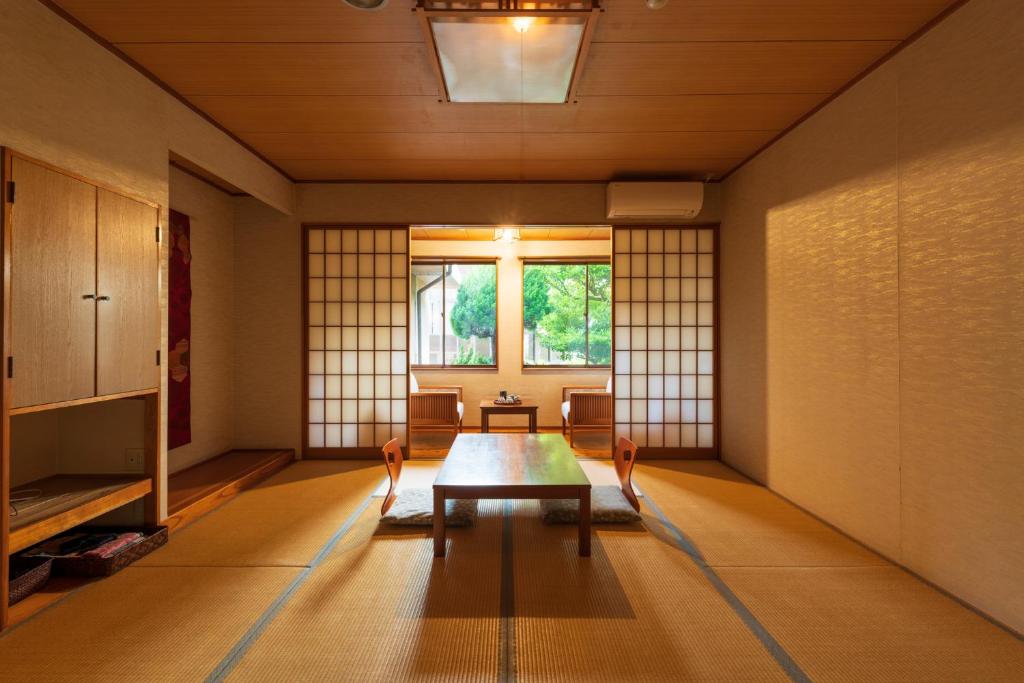 une pièce avec une table, des chaises et une fenêtre dans l'établissement Jyokiya, à Unzen