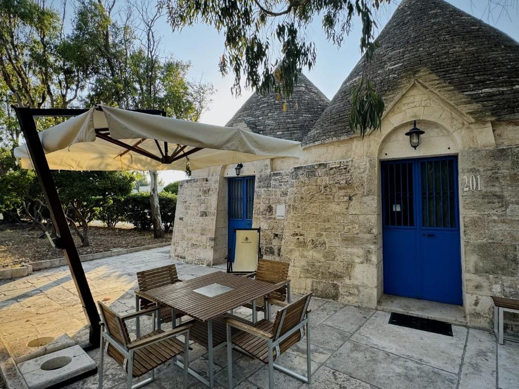une table avec des chaises et un parasol devant un bâtiment dans l'établissement Baia Sangiorgio Hotel & Beach Club, à Bari
