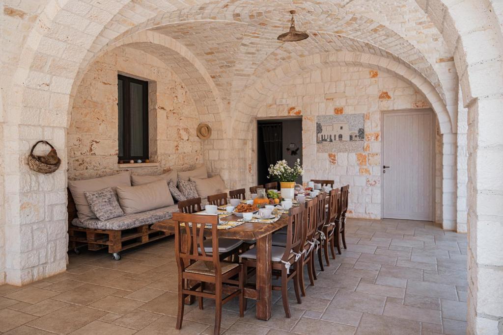 une salle à manger avec une table et un canapé dans l'établissement HelloApulia - Masseria Petra Antica - Charming Family Retreat with Private Pool in Itria Valle, à Ceglie Messapica