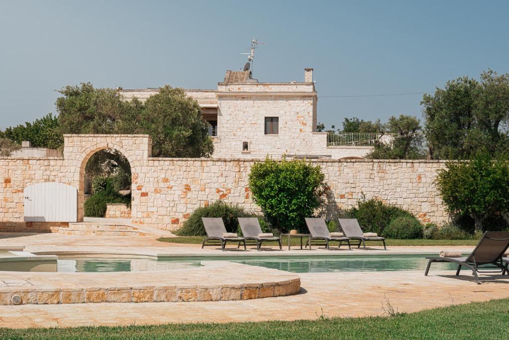 un groupe de chaises assises devant un bâtiment dans l'établissement HelloApulia - Masseria Petra Antica - Charming Family Retreat with Private Pool in Itria Valle, à Ceglie Messapica