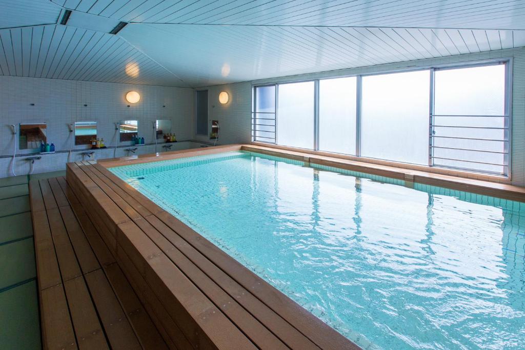 une grande piscine intérieure avec une grande fenêtre dans l'établissement Wasuki Tsukasakan, à Kumamoto