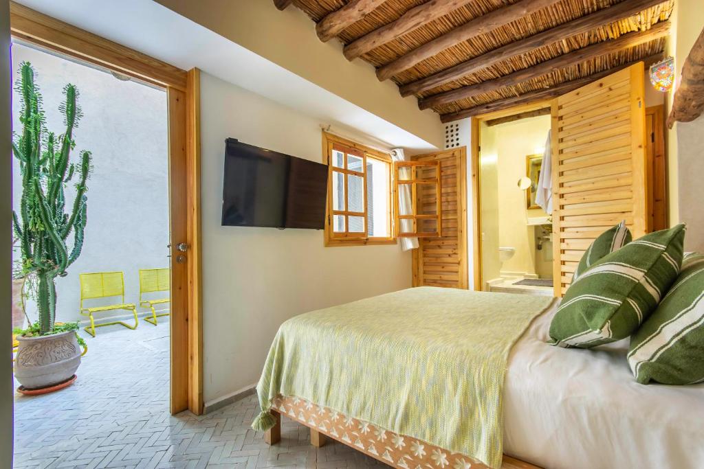 une chambre avec un lit et une télévision à écran plat dans l'établissement Riad Les Suites Marrakech, à Marrakech