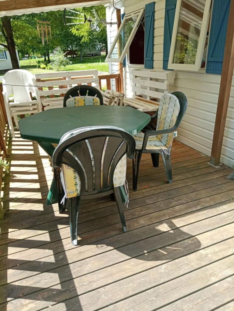 une table et des chaises vertes sur une terrasse couverte dans l'établissement Mobil-home au camping de bairon, à Le Chesne