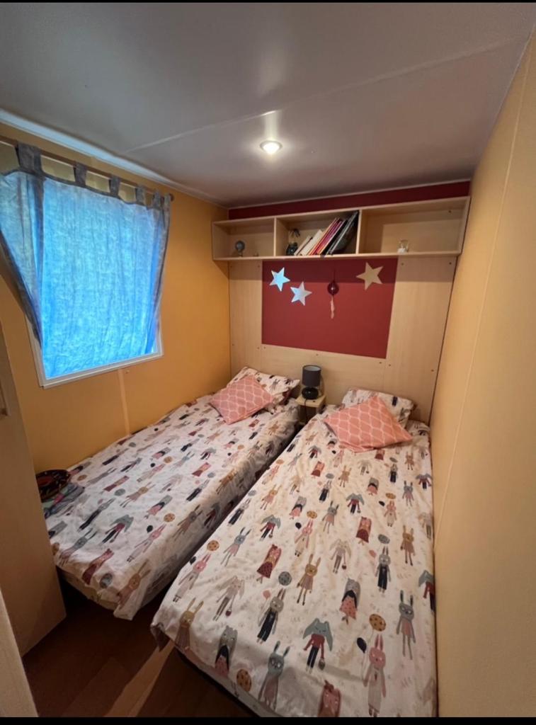 - 2 lits dans une petite chambre avec un couvre-lit dans l'établissement Mobil-home au camping de bairon, à Le Chesne