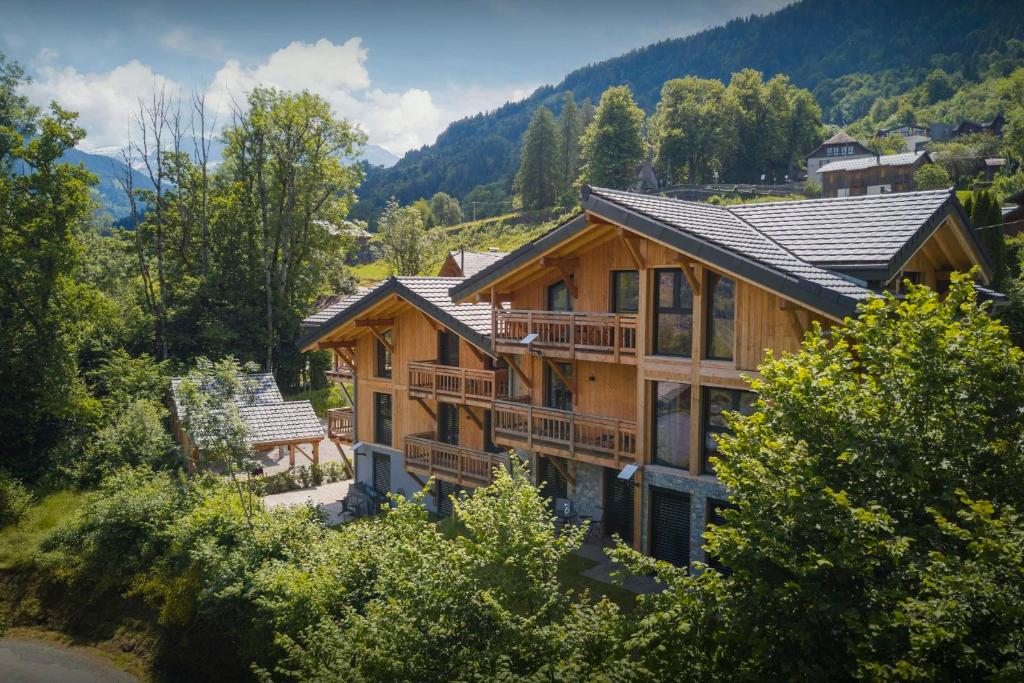 une image d'une maison en rondins avec des montagnes en arrière-plan dans l'établissement MontCriou - OVO Network, à Samoëns