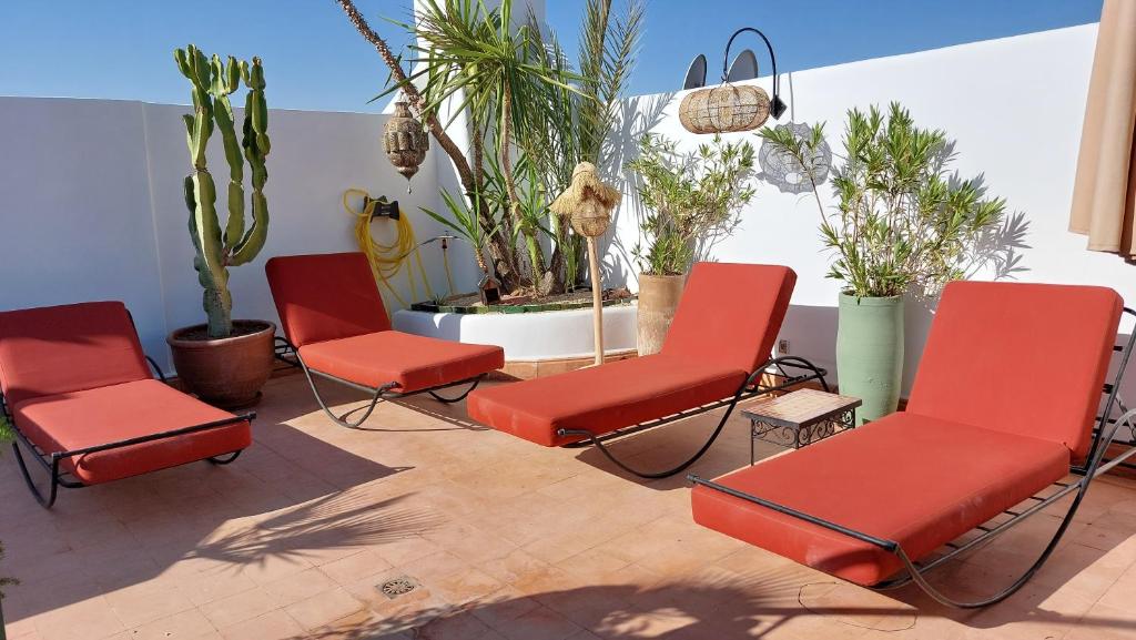 - un ensemble de chaises rouges assises sur une terrasse dans l'établissement Riad Cosy, à Marrakech