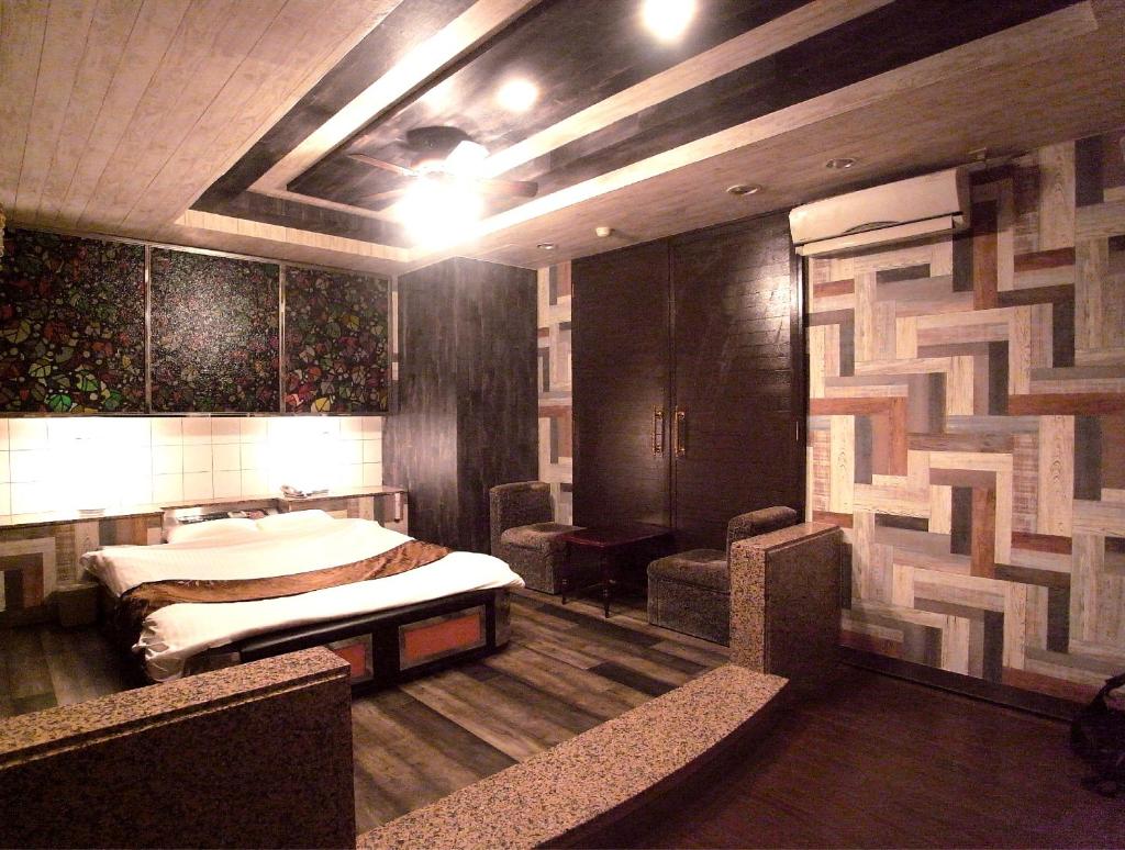 une chambre avec un lit et des chaises dans l'établissement ホテル暴れ狸の鬼袋姫路駅前店 男塾ホテルグループ, à Himeji