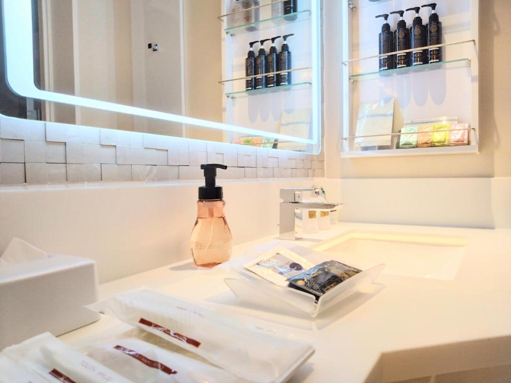 une salle de bain avec un lavabo avec une bouteille sur un comptoir dans l'établissement HOTEL The GRAF Matsubara, à Miyake