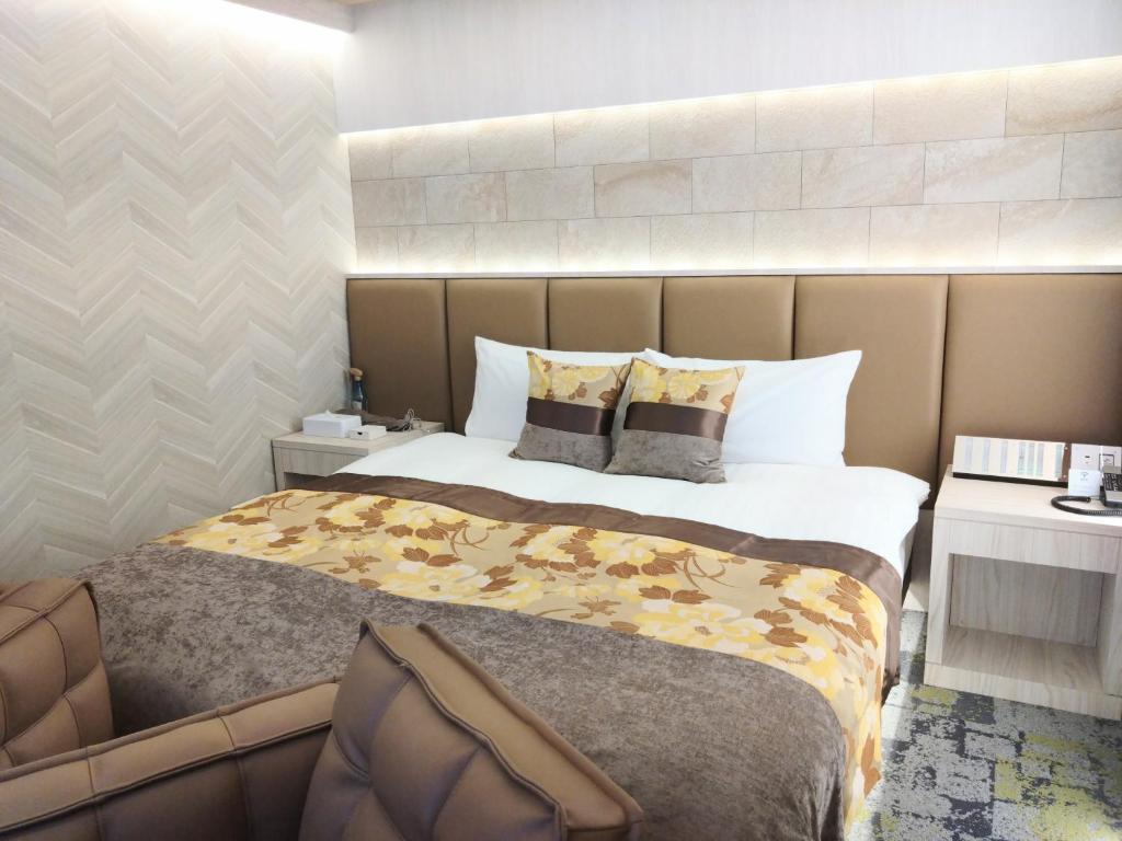 une chambre avec un grand lit avec une tête de lit dans l'établissement HOTEL The GRAF Matsubara, à Miyake