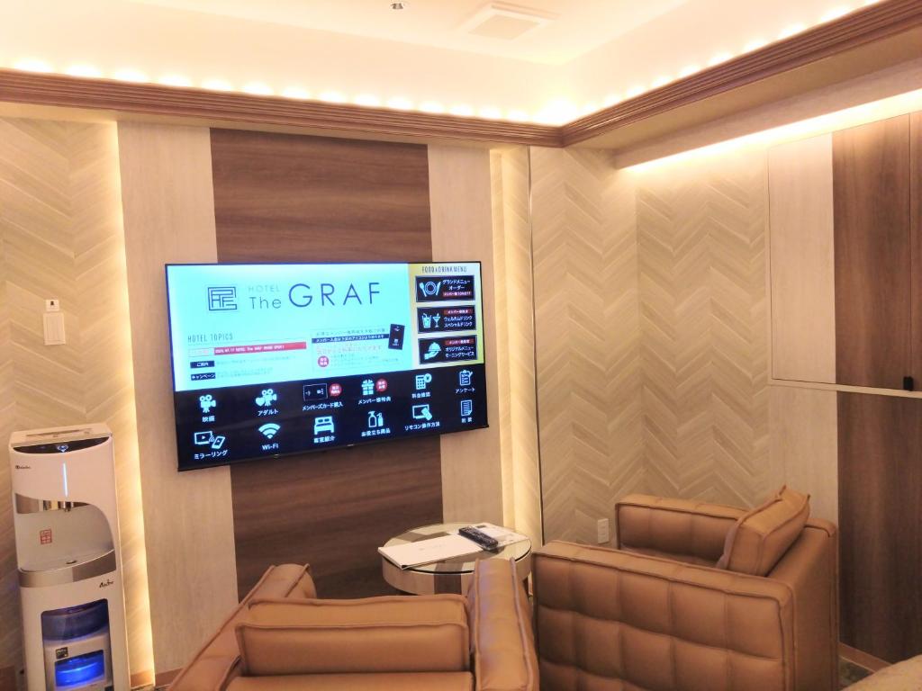 Cette chambre comprend deux chaises et une télévision à écran plat. dans l'établissement HOTEL The GRAF Matsubara, à Miyake