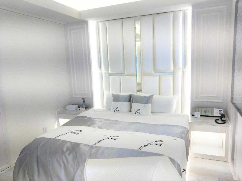 deux lits dans une chambre aux murs blancs dans l'établissement HOTEL The GRAF Matsubara, à Miyake 2 autres photos