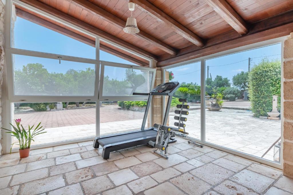 une salle de sport avec un tapis roulant et de grandes fenêtres dans l'établissement Masseria Pitorrè with private pool, à Conversano