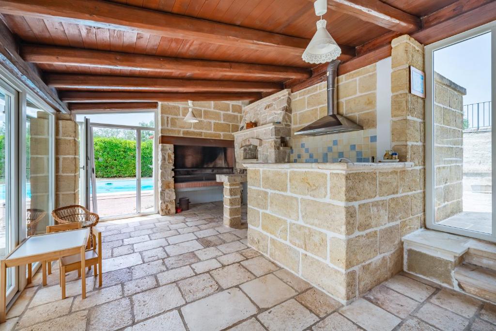 une grande cuisine en pierre avec une cheminée en pierre dans l'établissement Masseria Pitorrè with private pool, à Conversano