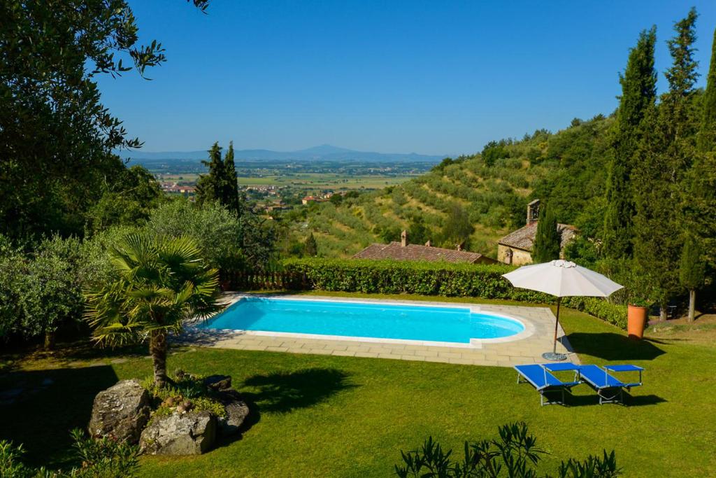 - une piscine dans une cour avec 2 chaises et un parasol dans l'établissement Villa Le Celle Del Farinaio, à Cortone