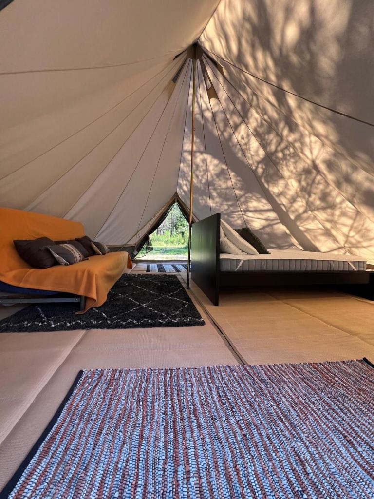 une tente avec un lit et un tapis dans une chambre dans l'établissement Camping la Kahute - Tente lodge au coeur de la forêt, à Carcans
