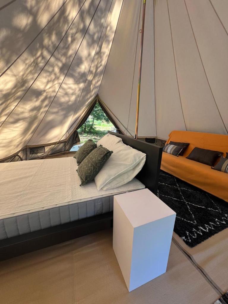 - un lit sur un voilier avec une table blanche et une boîte dans l'établissement Camping la Kahute - Tente lodge au coeur de la forêt, à Carcans 37 autres photos