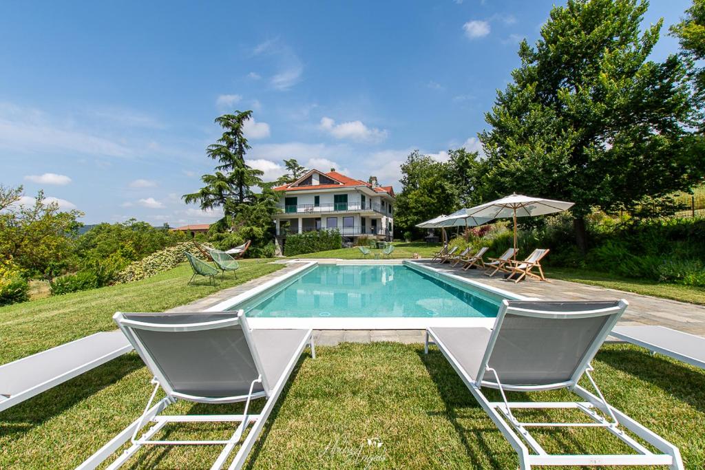 une piscine avec deux chaises et une maison dans l'établissement Villa Fiori, à Moncalvo