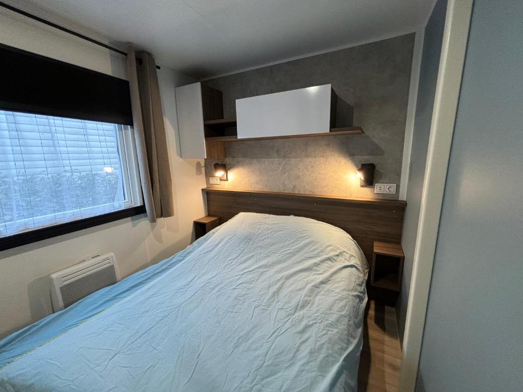 une petite chambre avec un lit et une fenêtre dans l'établissement Mobil home 253 Camping La Réserve 4 étoiles à Gastes, à Gastes