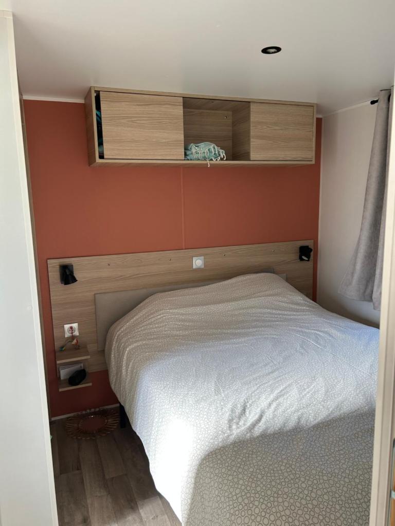 Ce lit se trouve dans un dortoir doté d'un mur orange. dans l'établissement Bungalow Port Grimaud 177, à Grimaud