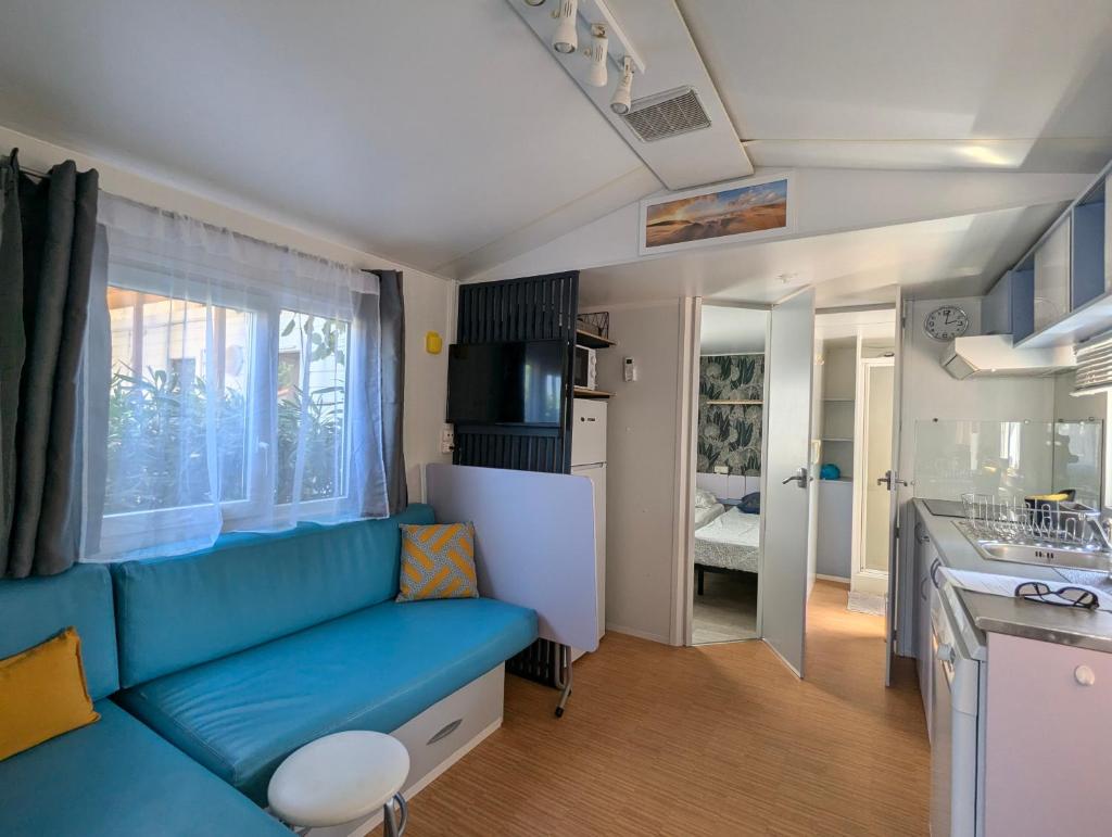 un salon avec un canapé bleu et une cuisine dans l'établissement Mobilhome avec piscine- plage à 10 minutes, à Saint-Aygulf
