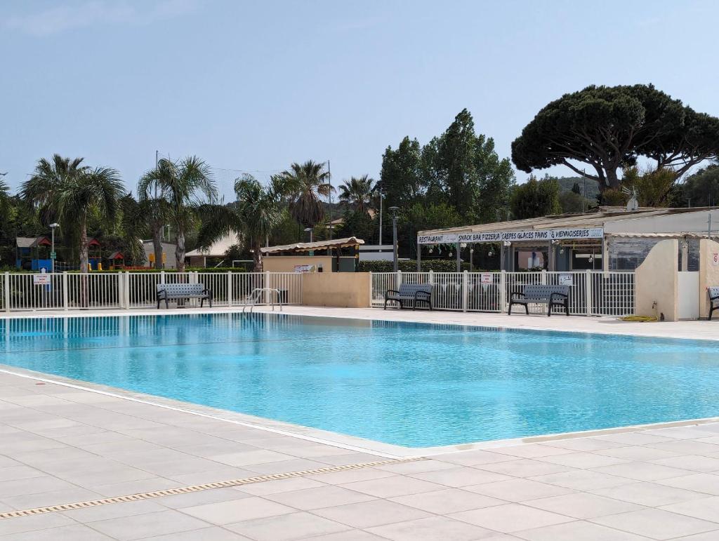 une grande piscine avec des chaises et des arbres en arrière-plan dans l'établissement Mobilhome avec piscine- plage à 10 minutes, à Saint-Aygulf