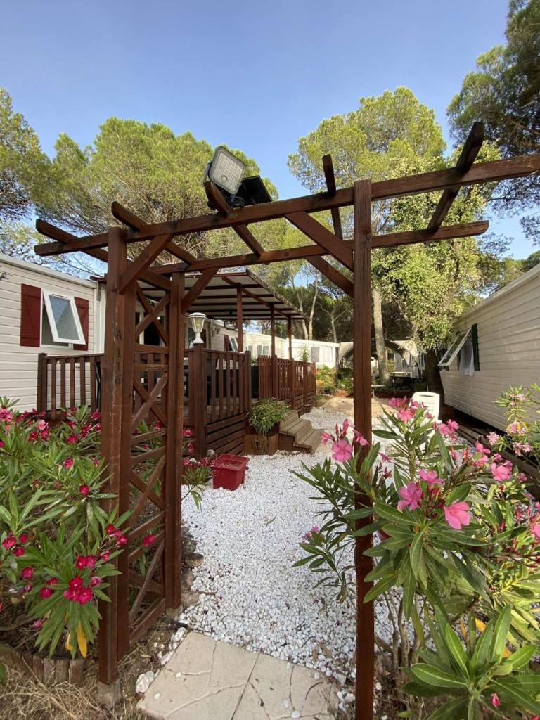 une pergola en bois dans une cour fleurie dans l'établissement Mobilhome paisible et verdoyant, à Puget-sur Argens