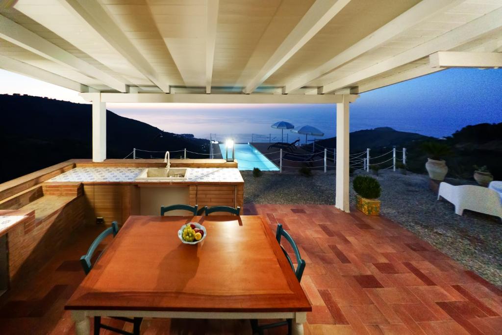 une table en bois sur une terrasse avec vue sur une piscine dans l'établissement Villa Ruya Cefalù, à Cefalù