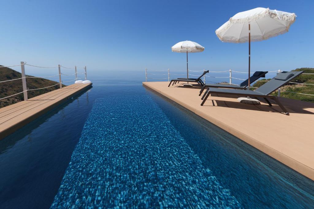 une piscine avec deux chaises et un parasol dans l'établissement Villa Ruya Cefalù, à Cefalù