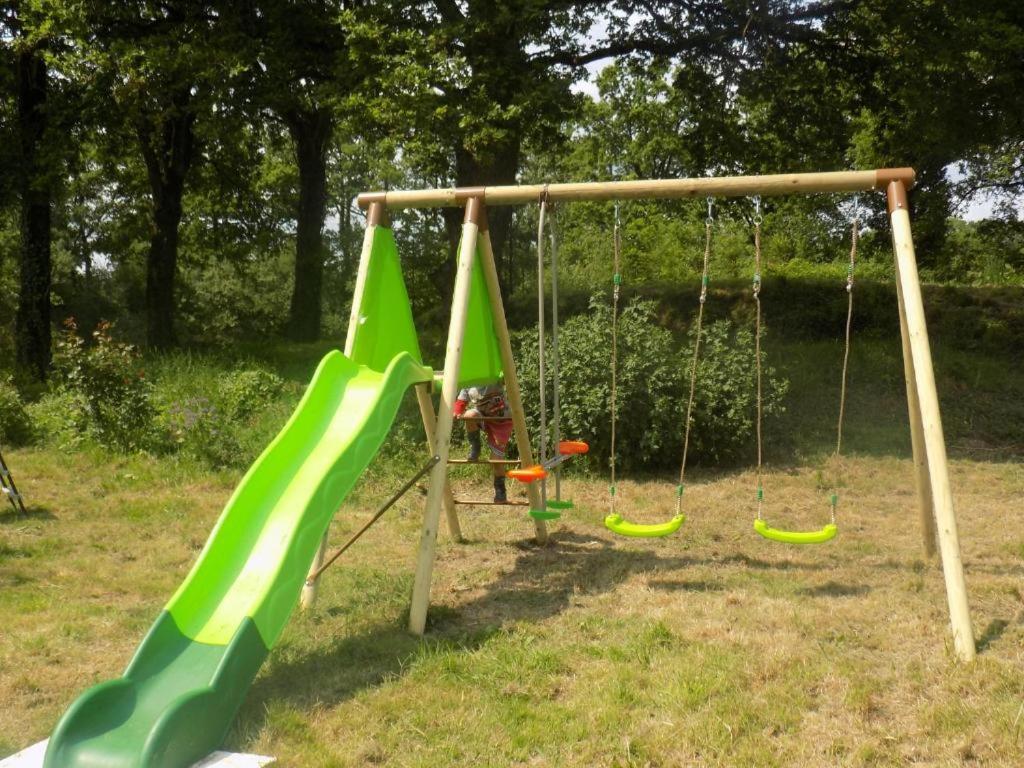 une aire de jeux avec des balançoires vertes dans un parc dans l'établissement Caravan du Loch, à Gaël