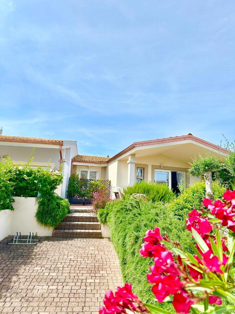 une maison avec des fleurs rouges devant elle dans l'établissement Villa Neni - Key to Villas, à Valledoria