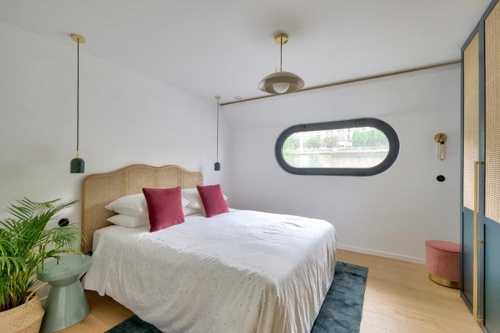 une chambre avec un lit blanc avec des oreillers rouges dans l'établissement Beautiful boathouse in Paris for JO, à Puteaux