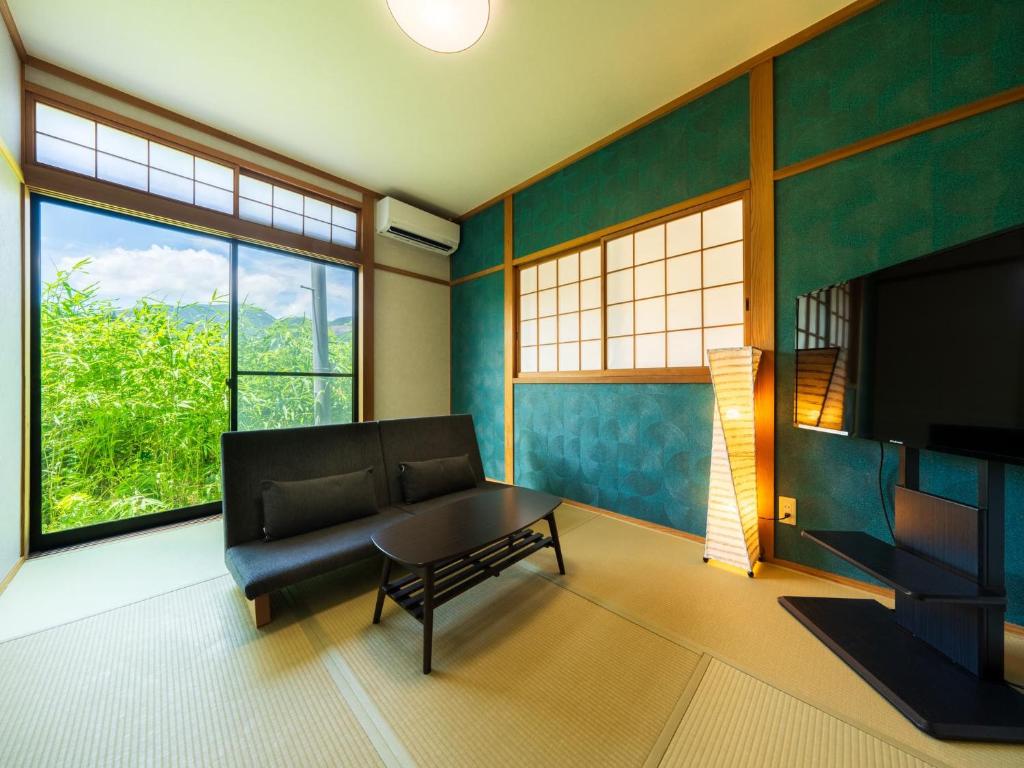 - un salon avec un canapé, une table et des fenêtres dans l'établissement Yufuin Hanarenoyado Yukagetsu, à Yufu