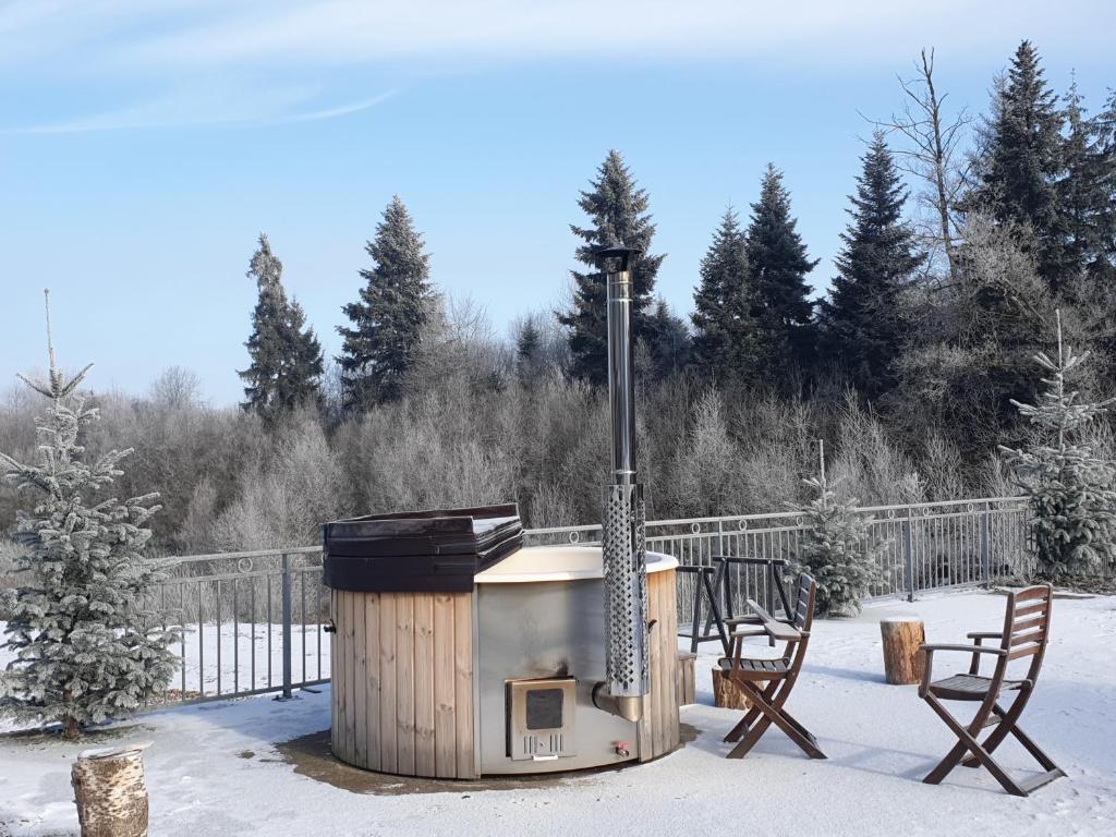 un barbecue au feu de bois dans la neige avec deux chaises dans l'établissement White wood lodge, à Nonville
