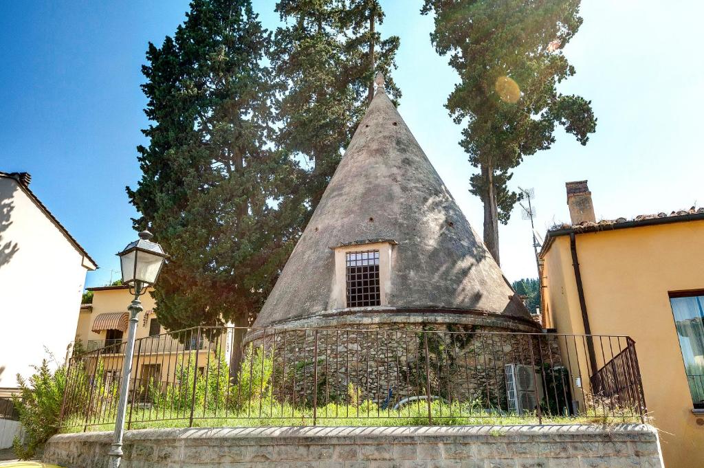 une maison avec un toit de chaume et une clôture dans l'établissement La Ghiacciaia magica !, à Calenzano