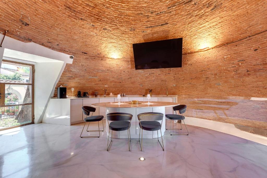 Il comprend une cuisine avec une table et des chaises ainsi qu'une télévision sur un mur en briques. dans l'établissement La Ghiacciaia magica !, à Calenzano